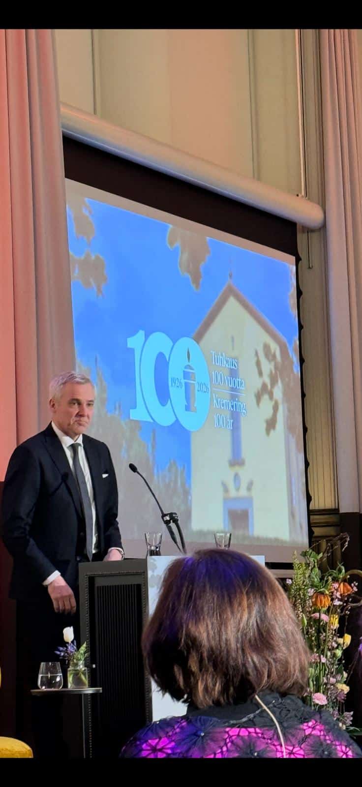 Tuhkaus 100 vuotta Suomessa — Humat juhlisti krematoriosäätiön satavuotisjuhlia 3 Marcus Rantala avaa krematoriosäätiön 100-vuotisjuhlaseminaarin, Tuhkaus 100 vuotta -juliste taustalla