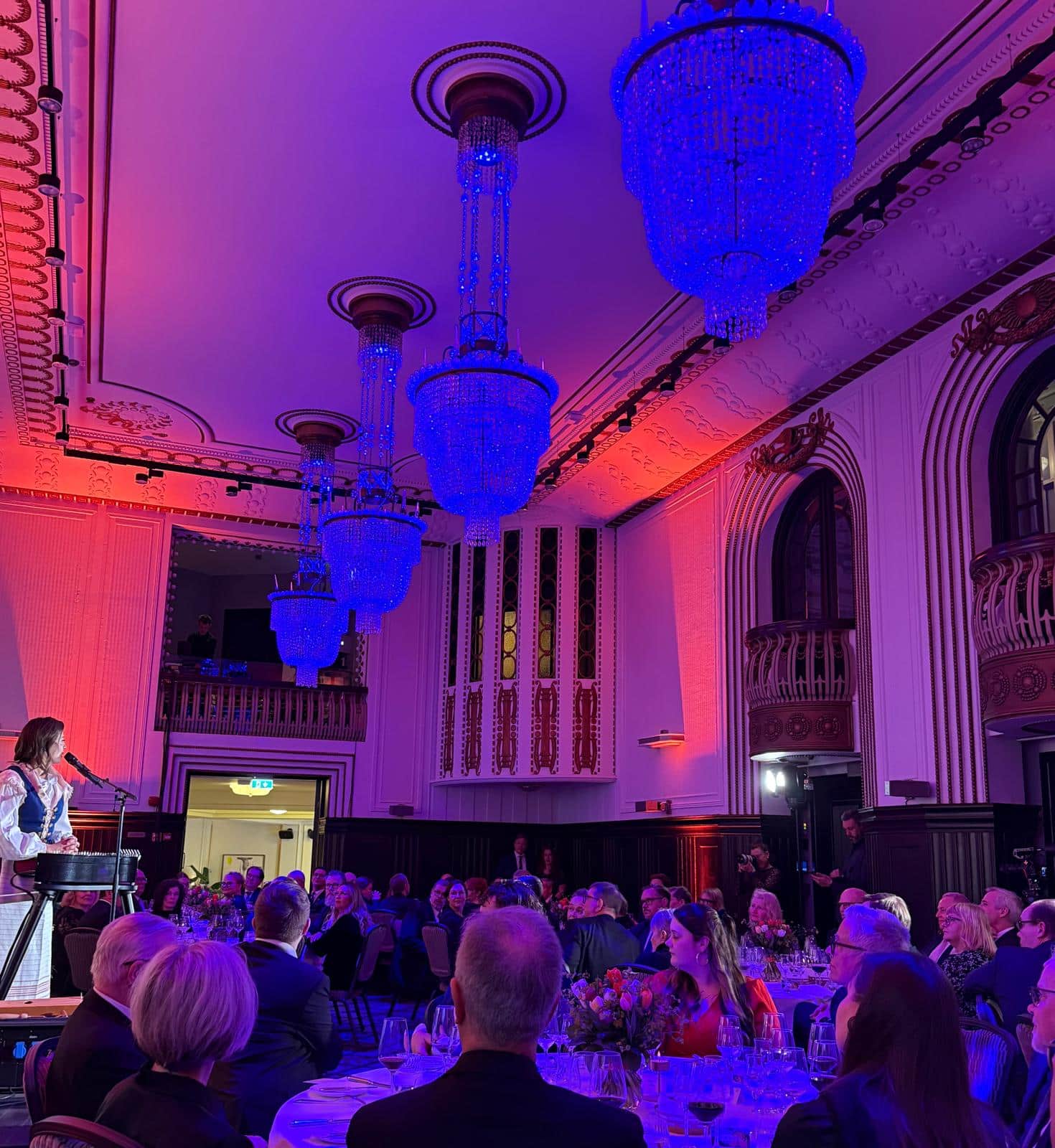 Tuhkaus 100 vuotta Suomessa — Humat juhlisti krematoriosäätiön satavuotisjuhlia 6 Juhlaillallinen Grand Hansassa, sinisessä valossa hehkuvat kristallikruunut